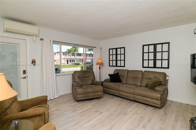 living room featuring a textured ceiling, a wall unit AC, and light hardwood / wood-style flooring