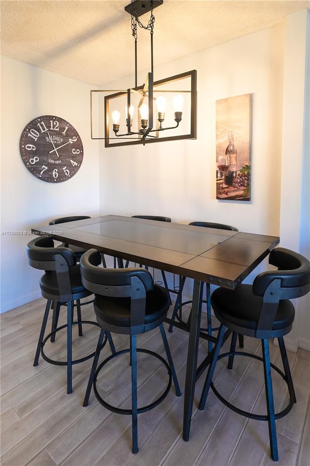 dining space with an inviting chandelier, hardwood / wood-style flooring, and a textured ceiling