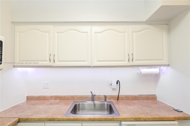 kitchen with dishwashing machine, sink, decorative backsplash, and white cabinets