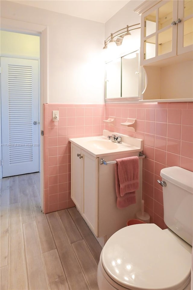 bathroom with vanity, tile walls, and toilet