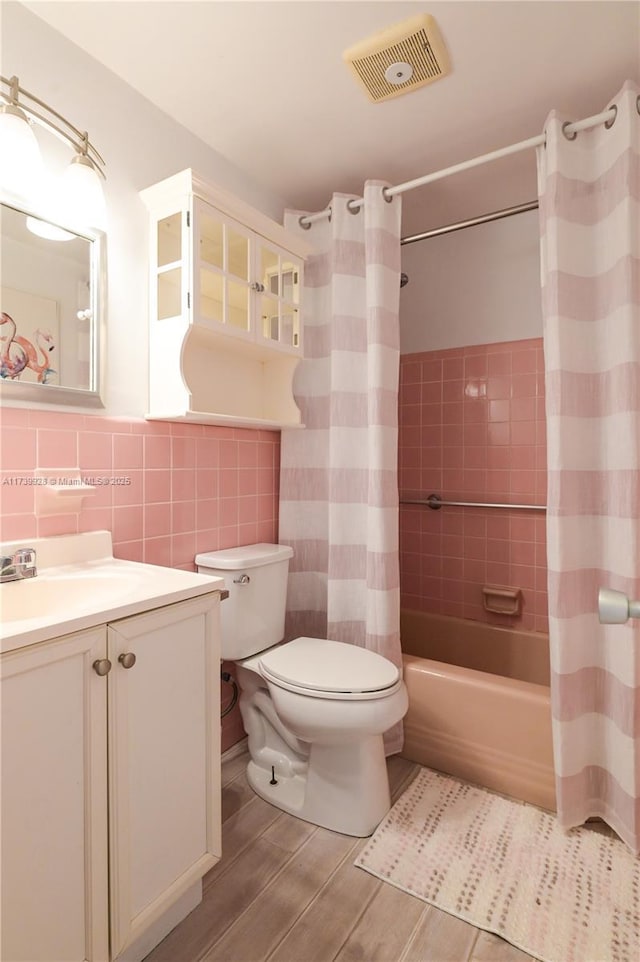 full bathroom with tile walls, vanity, toilet, and shower / bathtub combination with curtain