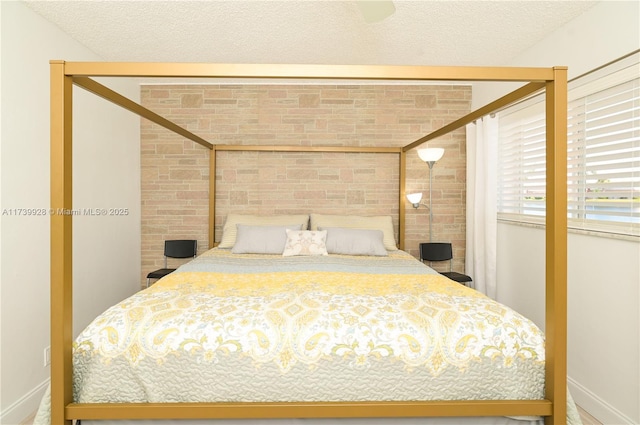 bedroom with a textured ceiling and brick wall