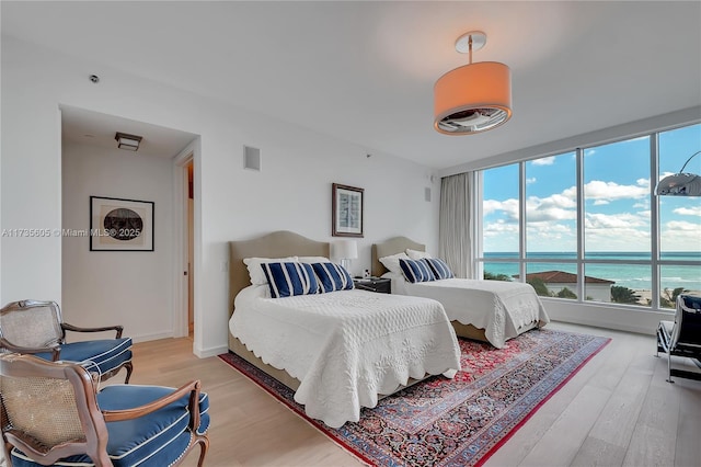 bedroom with light wood-type flooring and a water view