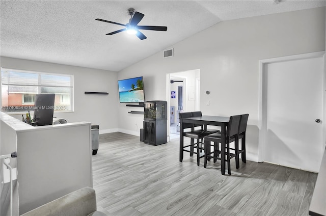 dining space featuring vaulted ceiling, ceiling fan, light hardwood / wood-style floors, and a textured ceiling