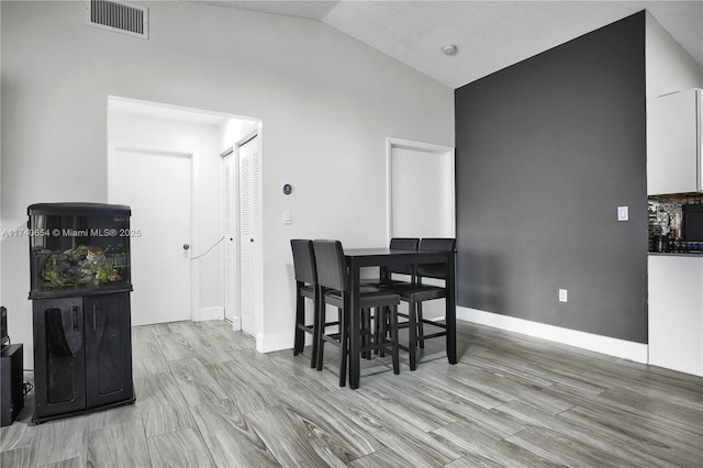 dining space with lofted ceiling and light hardwood / wood-style floors