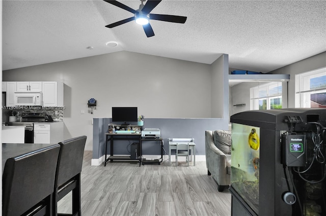 interior space featuring vaulted ceiling, white cabinets, stainless steel range with electric cooktop, decorative backsplash, and light wood-type flooring