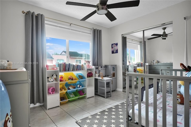 bedroom with ceiling fan, light tile patterned floors, and a textured ceiling