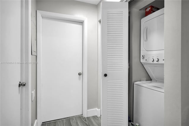 laundry room featuring stacked washer / drying machine and light hardwood / wood-style floors