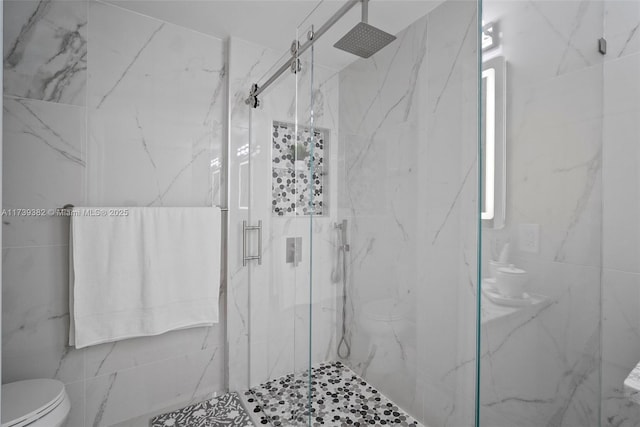 bathroom with a shower with shower door and toilet