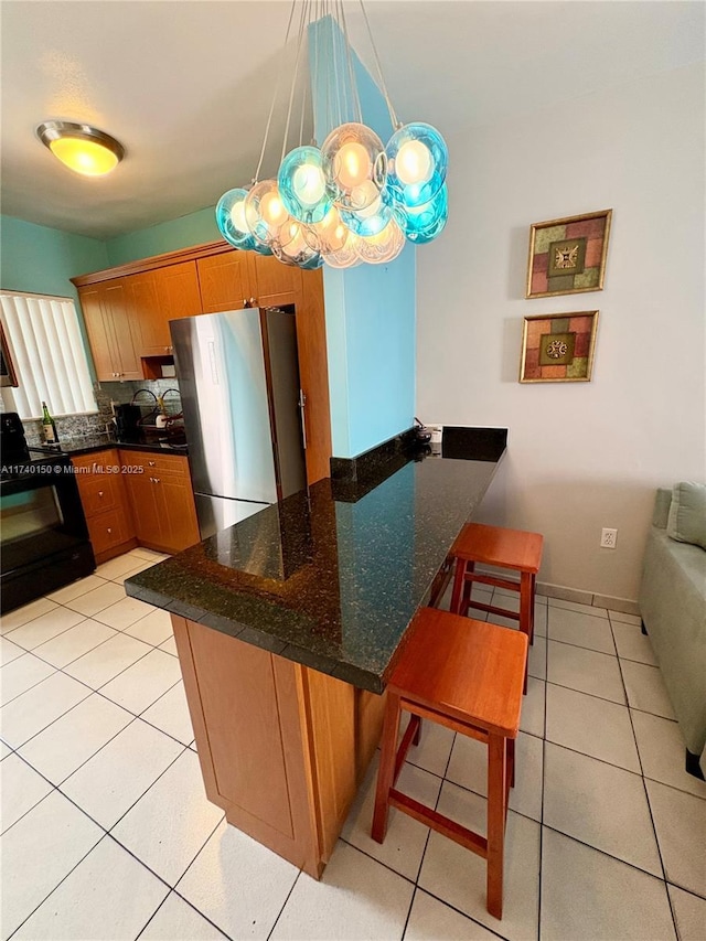 kitchen featuring pendant lighting, stainless steel refrigerator, a breakfast bar area, kitchen peninsula, and black electric range