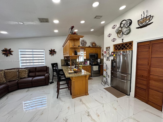 kitchen featuring a breakfast bar area, stone countertops, vaulted ceiling, kitchen peninsula, and stainless steel appliances