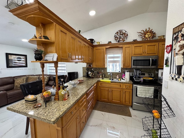 kitchen with stainless steel appliances, kitchen peninsula, sink, and a breakfast bar area