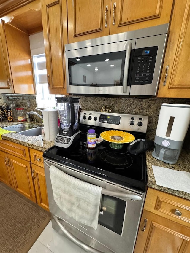 kitchen featuring sink, decorative backsplash, light stone countertops, and appliances with stainless steel finishes