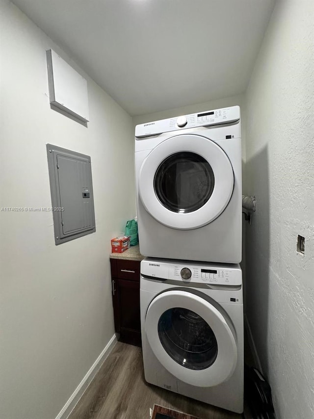 laundry room with stacked washer / dryer, cabinets, electric panel, and dark hardwood / wood-style flooring