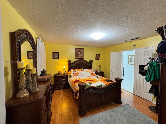 bedroom featuring light hardwood / wood-style floors and a textured ceiling