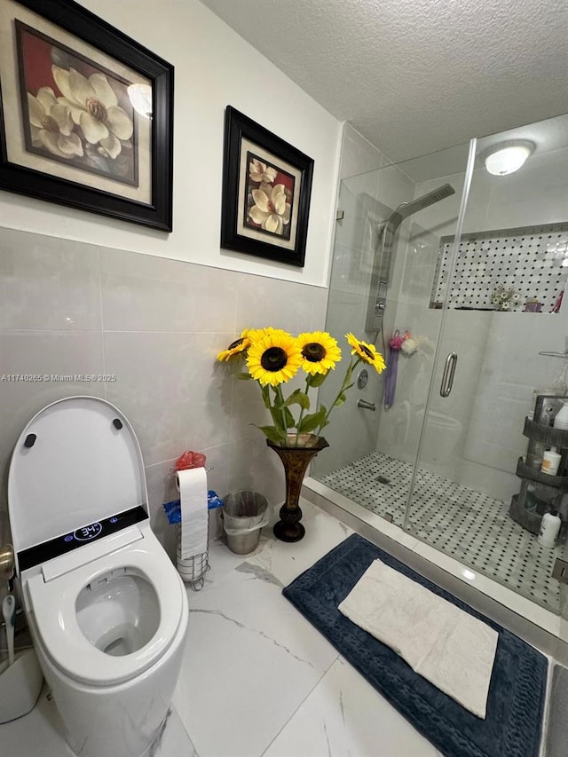 bathroom with a shower with shower door and a textured ceiling