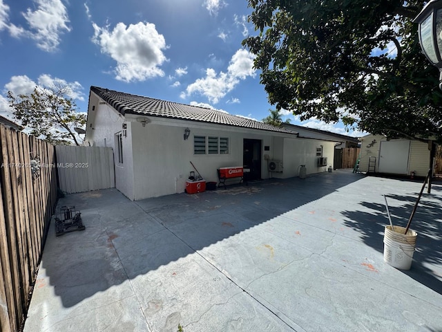 rear view of property with a shed and a patio area