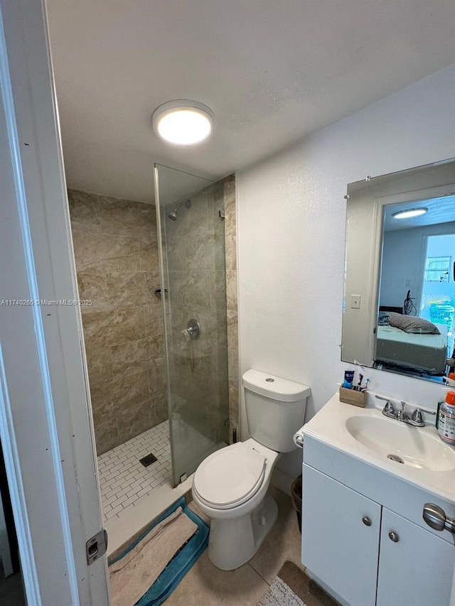 bathroom with tiled shower, vanity, toilet, and tile patterned flooring