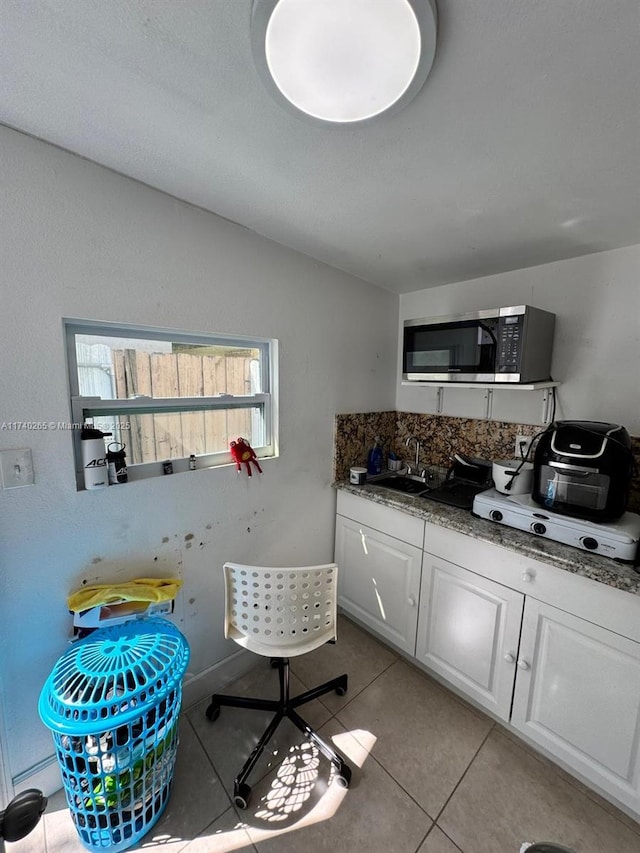 kitchen featuring light tile patterned flooring, white cabinetry, lofted ceiling, sink, and dark stone countertops