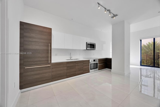 kitchen with light tile patterned flooring, sink, white cabinetry, appliances with stainless steel finishes, and backsplash