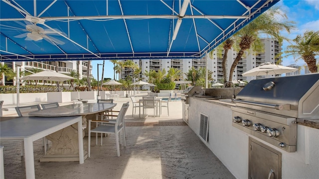 view of patio with exterior kitchen, a grill, ceiling fan, and an outdoor wet bar