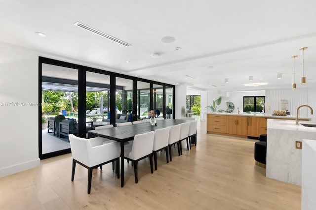 dining area with expansive windows, sink, and light wood-type flooring