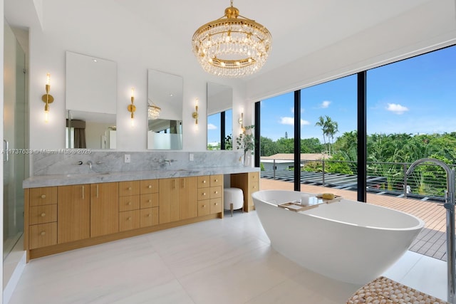 bathroom with vanity, a notable chandelier, backsplash, and a tub