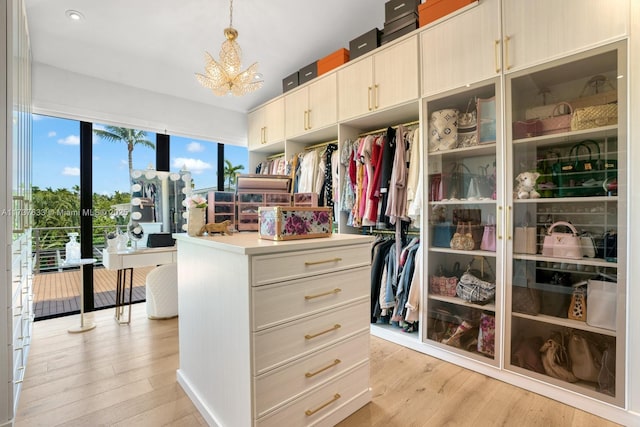 walk in closet with a chandelier and light hardwood / wood-style floors