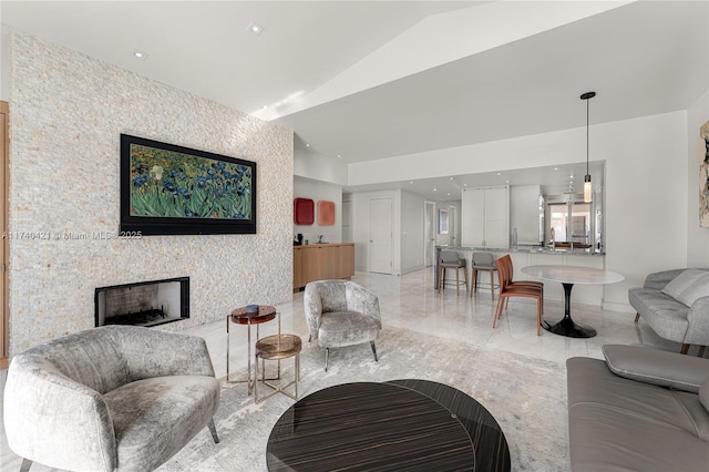 living room featuring vaulted ceiling, sink, and a fireplace