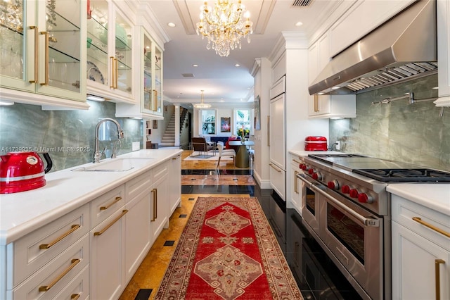 kitchen featuring range with two ovens, white cabinetry, sink, and exhaust hood