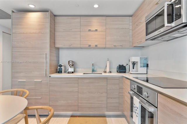 kitchen with light brown cabinetry, sink, and appliances with stainless steel finishes