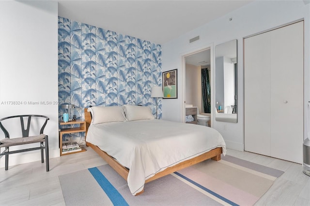 bedroom with light hardwood / wood-style floors and ensuite bath