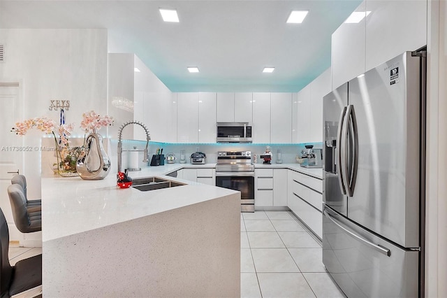 kitchen with stainless steel appliances, white cabinetry, sink, and light tile patterned floors