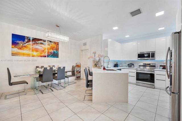 kitchen with pendant lighting, white cabinetry, sink, light tile patterned floors, and stainless steel appliances