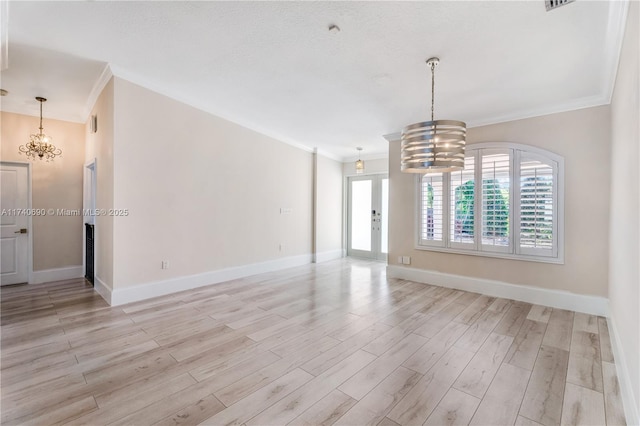 empty room with ornamental molding, light wood-type flooring, and a chandelier