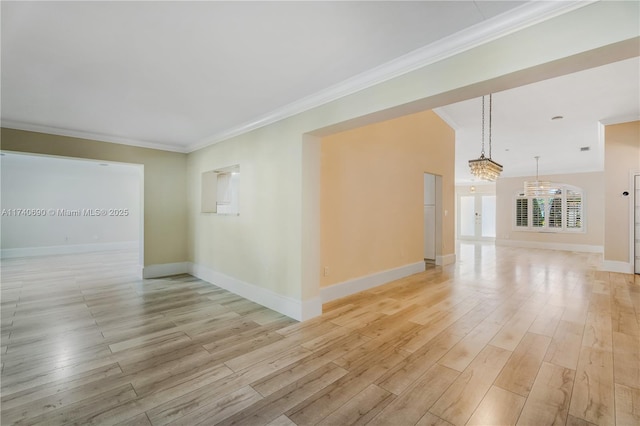 empty room featuring crown molding, an inviting chandelier, and light hardwood / wood-style flooring