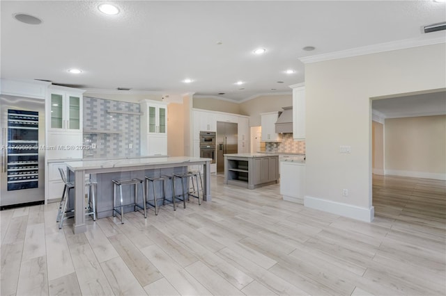 kitchen with appliances with stainless steel finishes, a kitchen island, white cabinets, decorative backsplash, and crown molding