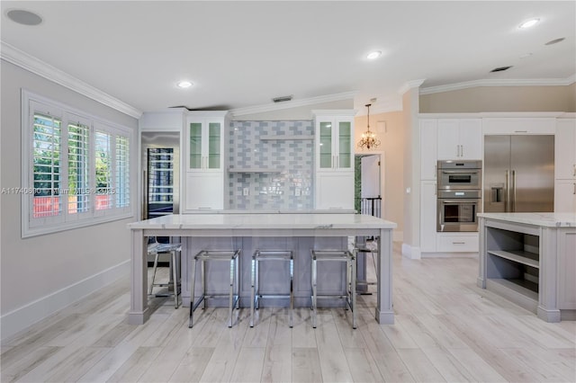 kitchen with white cabinetry, light stone counters, decorative light fixtures, appliances with stainless steel finishes, and decorative backsplash