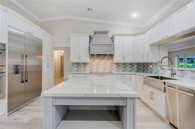 kitchen featuring lofted ceiling, sink, appliances with stainless steel finishes, light stone countertops, and white cabinets