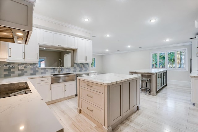 kitchen featuring sink, backsplash, a center island, black electric stovetop, and light stone countertops