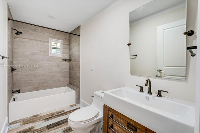 full bathroom featuring vanity, tiled shower / bath, and toilet