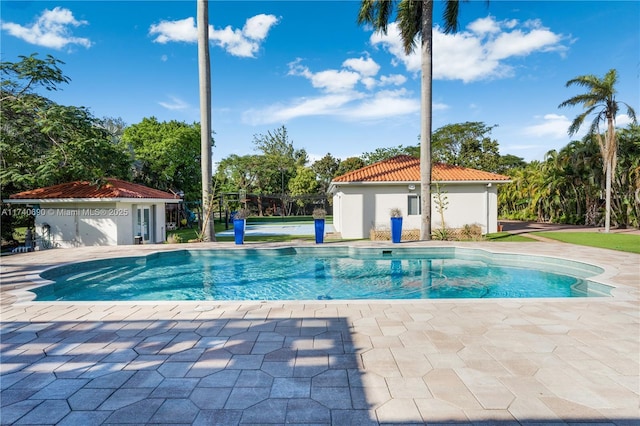 view of swimming pool featuring an outbuilding and a patio