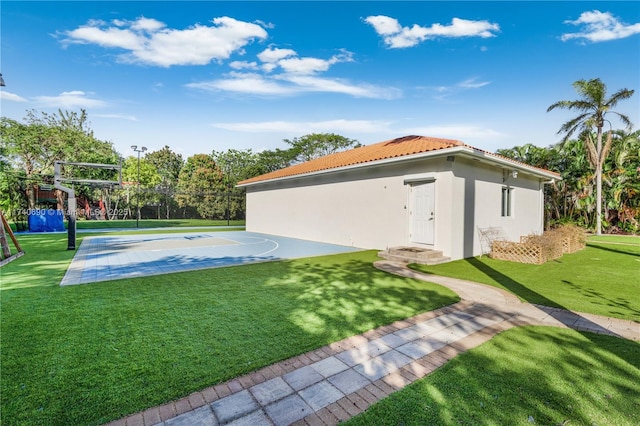 exterior space featuring basketball hoop and a lawn