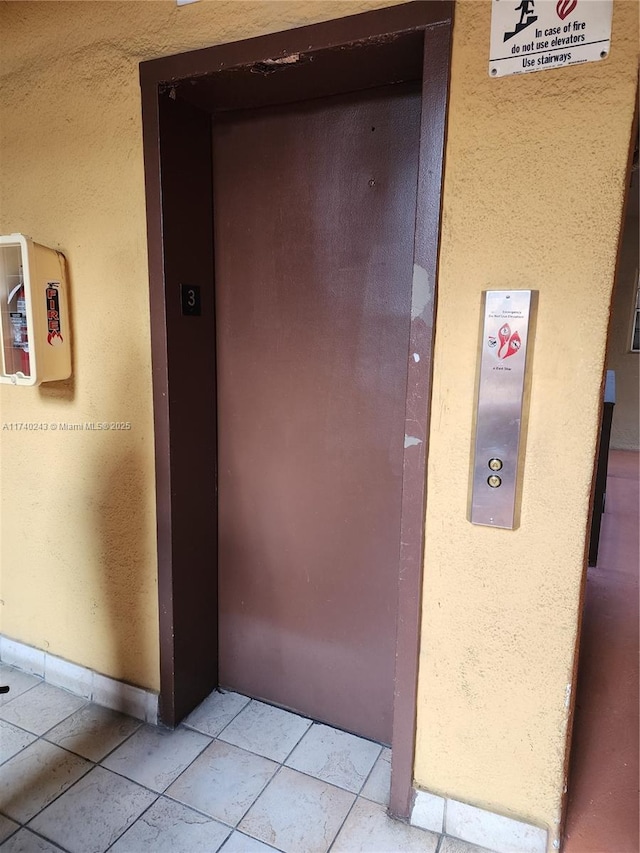 corridor with elevator and light tile patterned floors