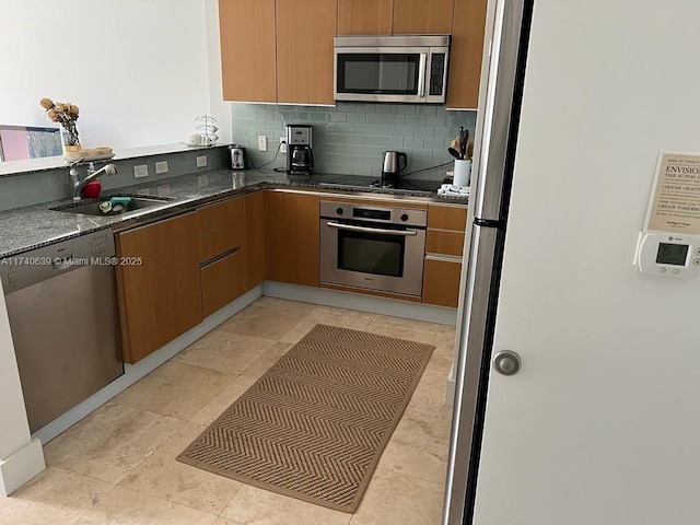 kitchen with tasteful backsplash, sink, dark stone countertops, and appliances with stainless steel finishes