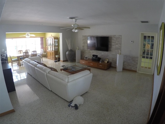 living room featuring ceiling fan, visible vents, and light speckled floor