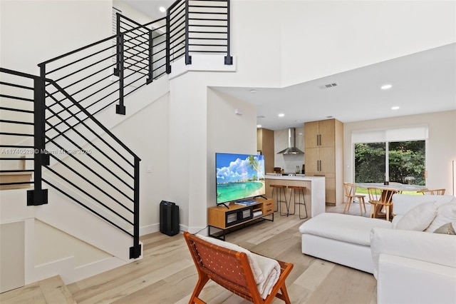 living room featuring a towering ceiling and light hardwood / wood-style flooring