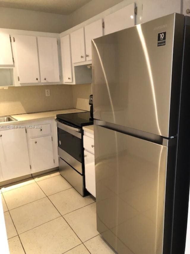 kitchen with light tile patterned floors, stainless steel appliances, and white cabinets