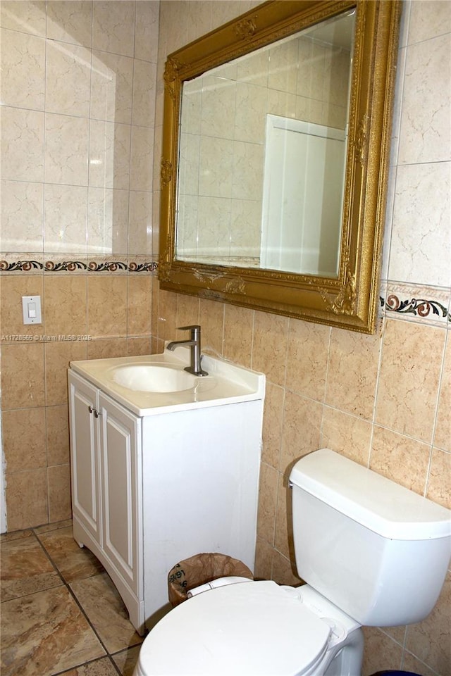 bathroom with vanity, toilet, and tile walls