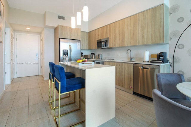 kitchen featuring a kitchen island, decorative light fixtures, sink, a kitchen breakfast bar, and stainless steel appliances